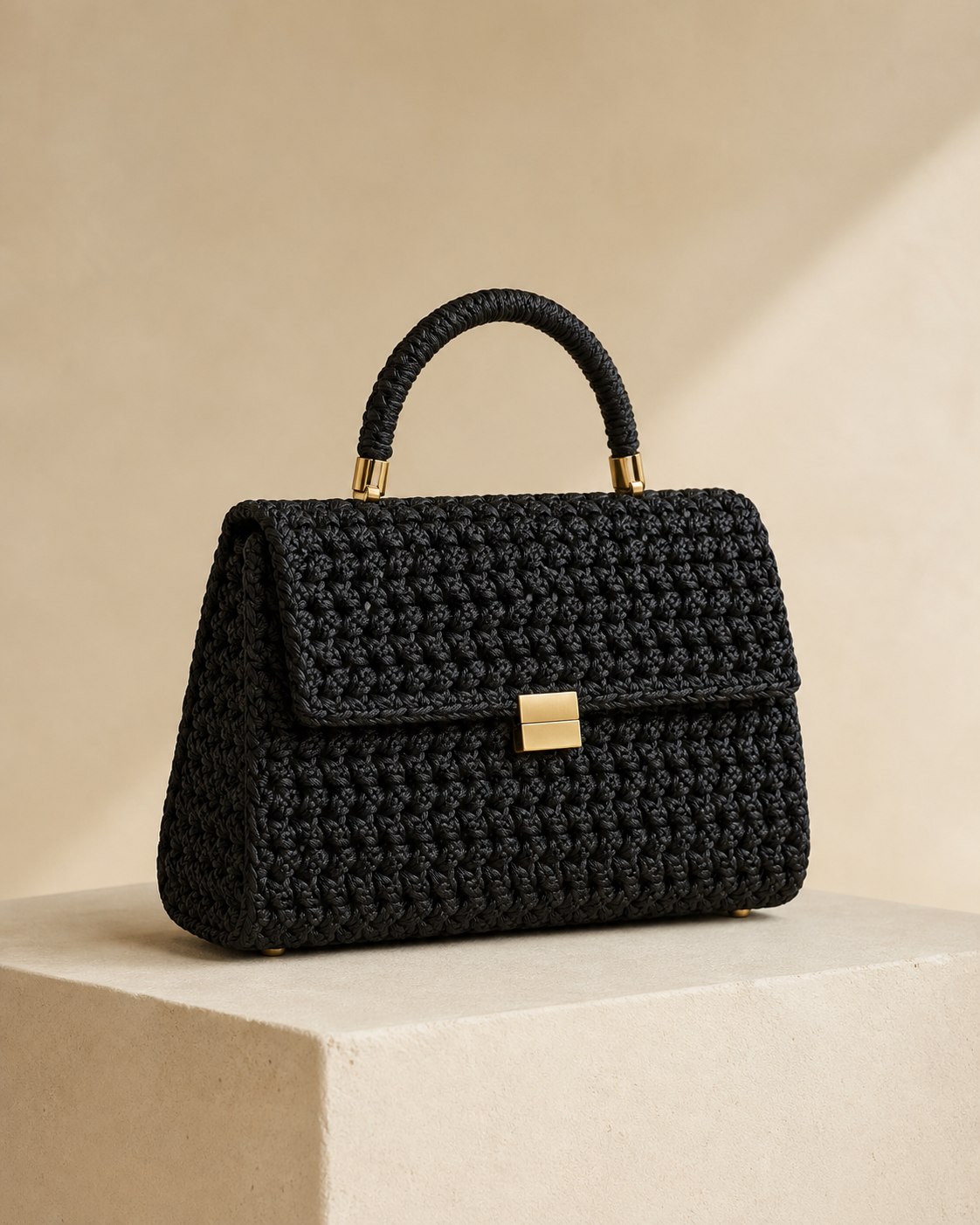 Bolsa Monte Noir preta sobre pedestal creme